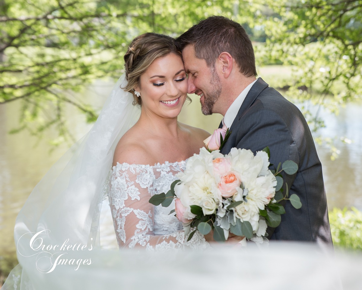 Wedding couple with long veil blowing in the wind at Waters Edge in Cape Girardeau. MO