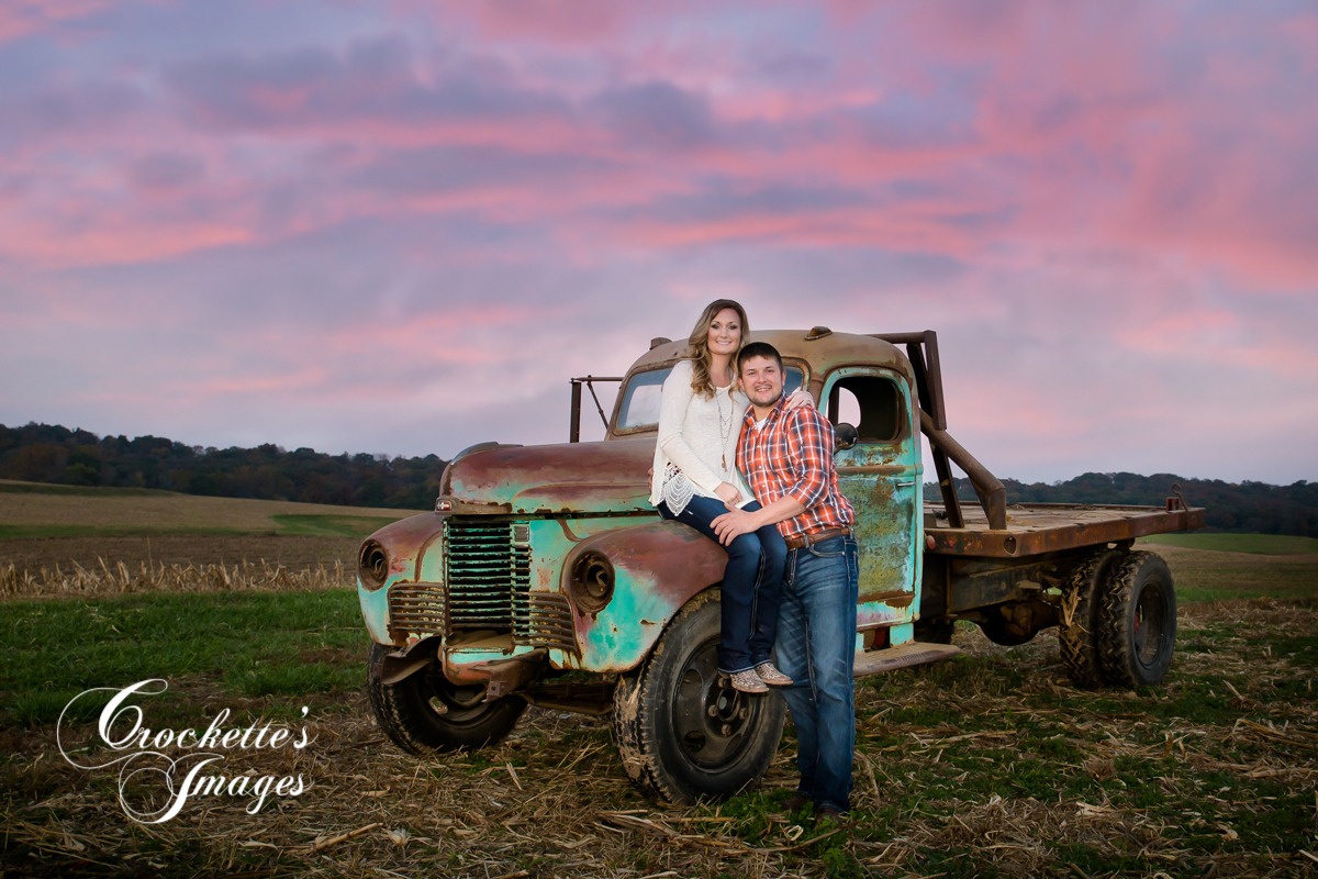 Country engagement photo with rustic truck on the farm at sunset.