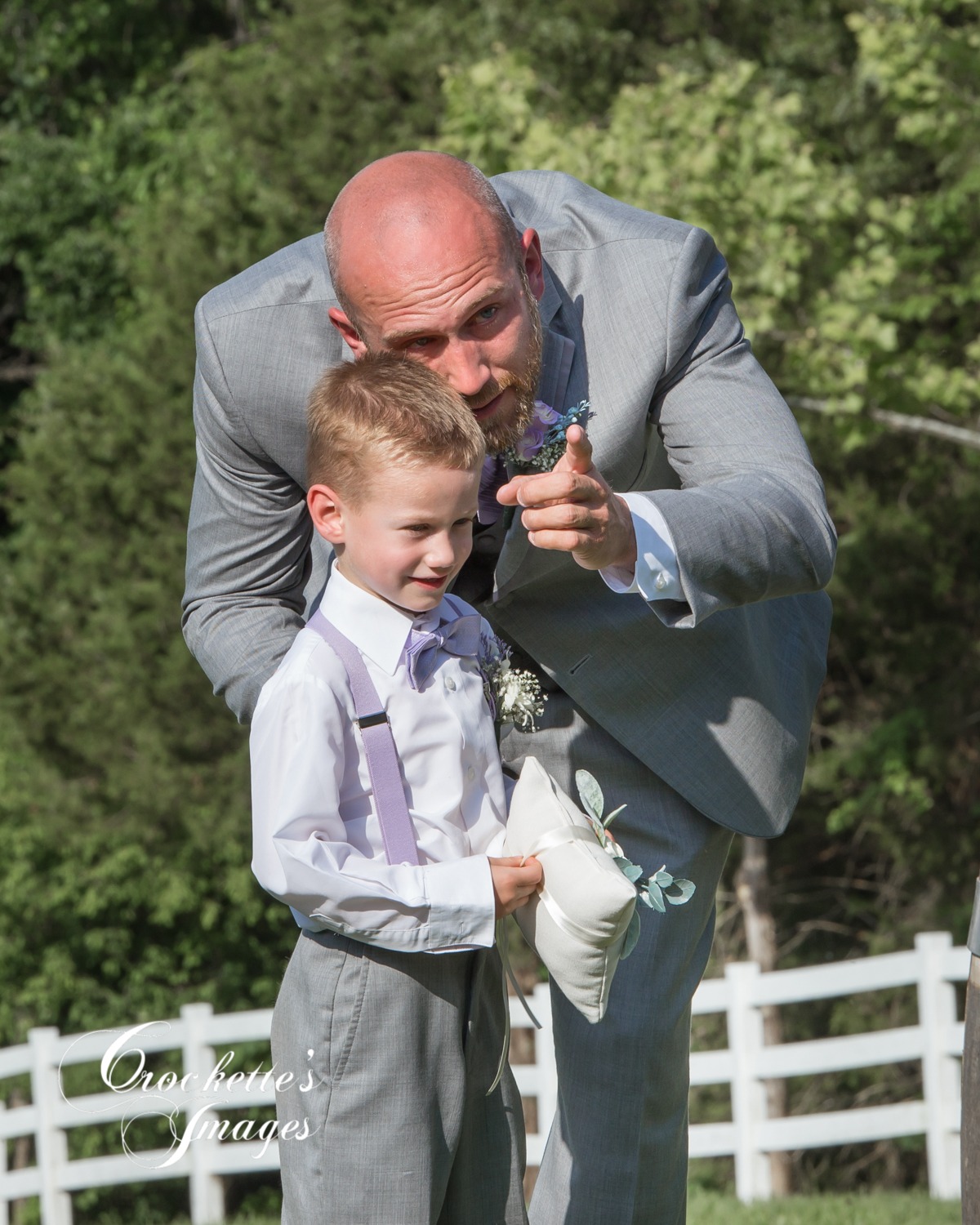 Dad and son look for mom to walk down the isle at an outdoor wedding ceremony