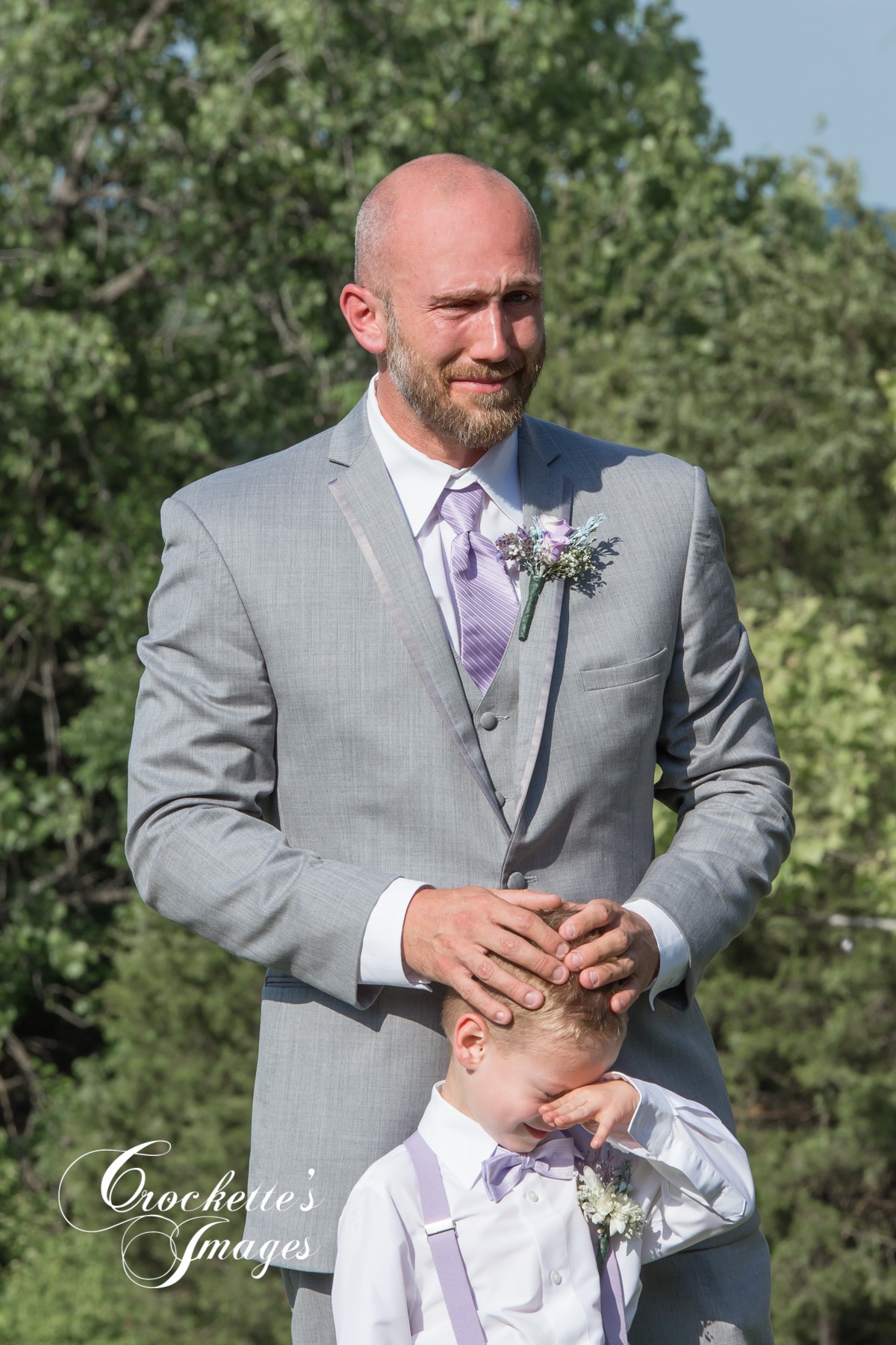 Dad and son see mom walk down the isle at an outdoor wedding ceremony