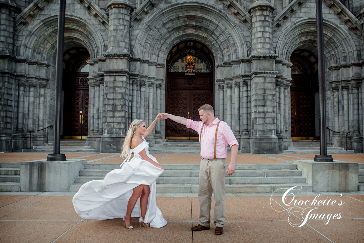 man twirling fiance in front of church