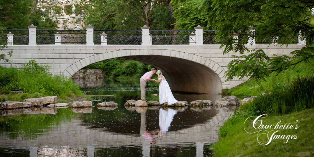 engagement photo in stream in front of stone bridge