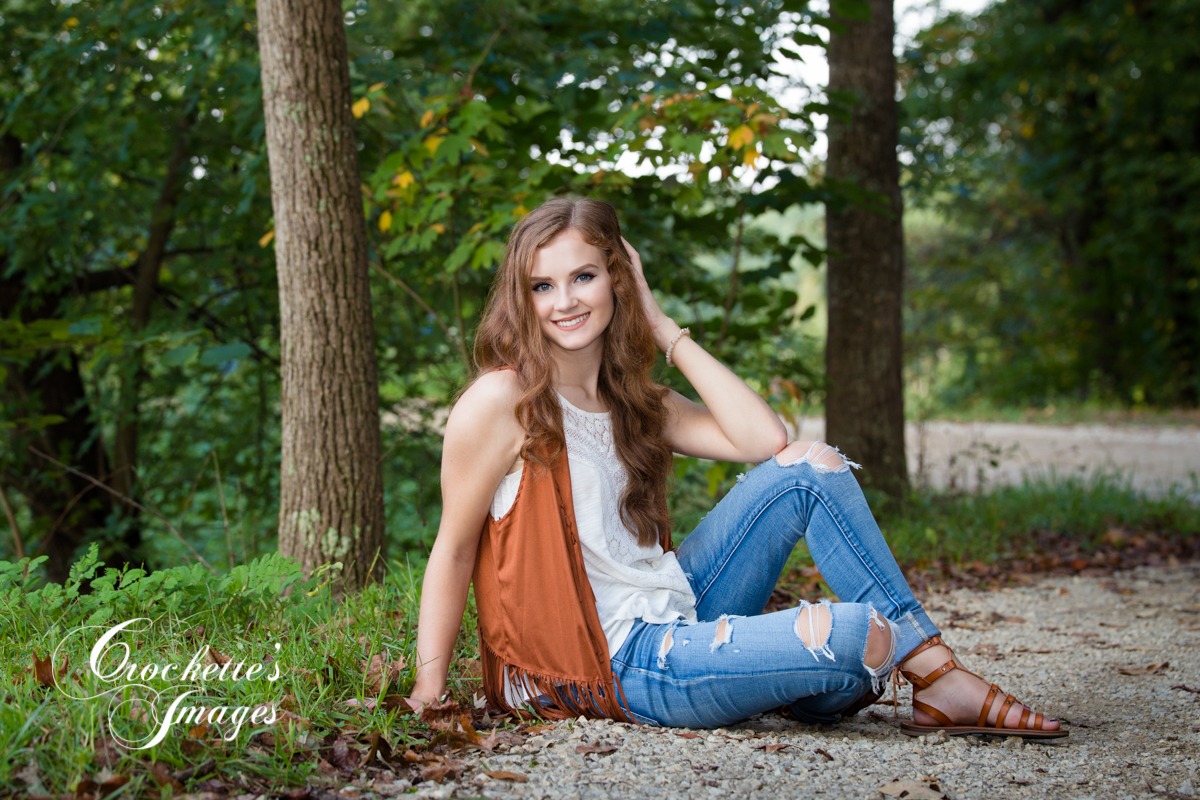 Summer senior photo with beautiful girl sitting on gravel road