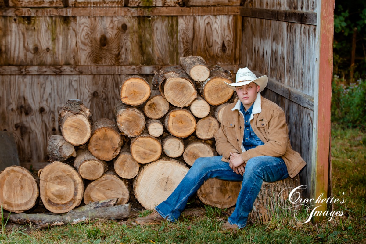 Country boy senior photos by a wood pile