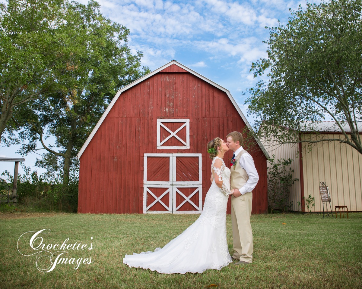 Farm Wedding with couple in front of a red barn kissing