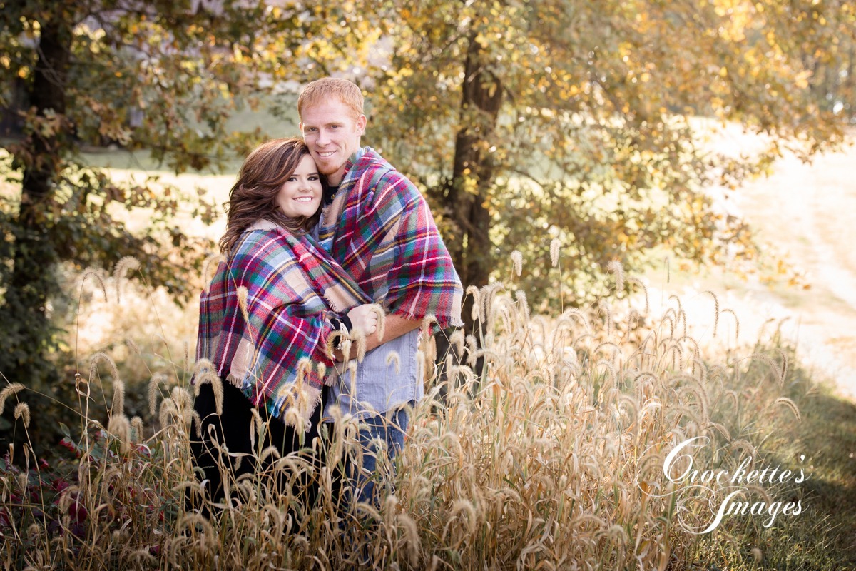 Fall engagement photo with couple in a foxtail field wraped in a blanket