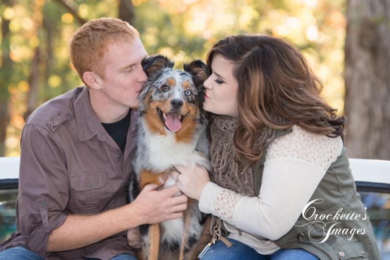 Fall engagement photo with couple kissing their dog
