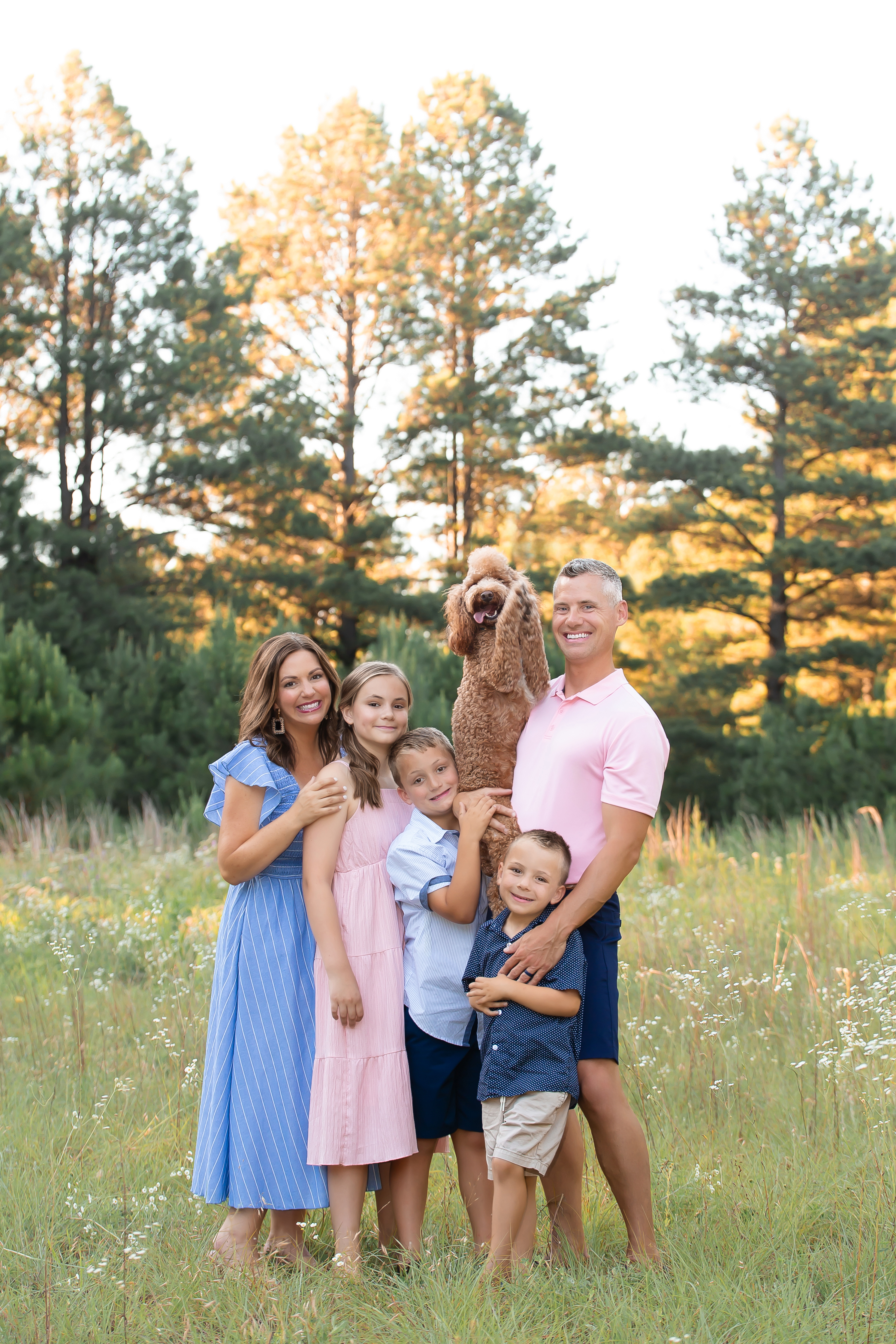 Spring Family Photo in the pine trees. Navy blue, Light, and light pink color scheme. Family Photos with a dog