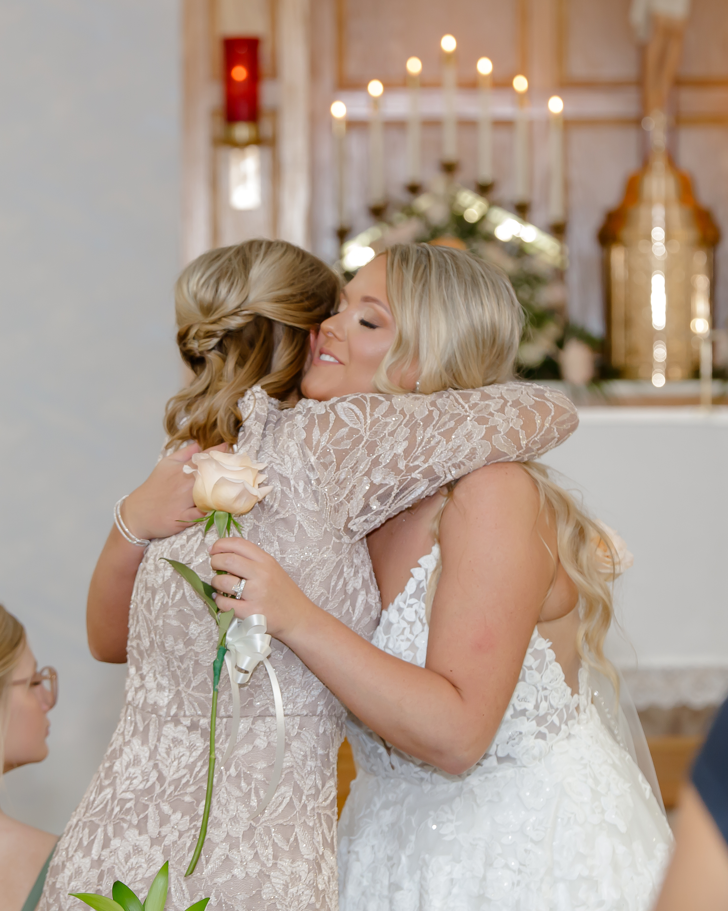 A bride giving her mother a flower and hug at a Catholic Wedding Ceremony