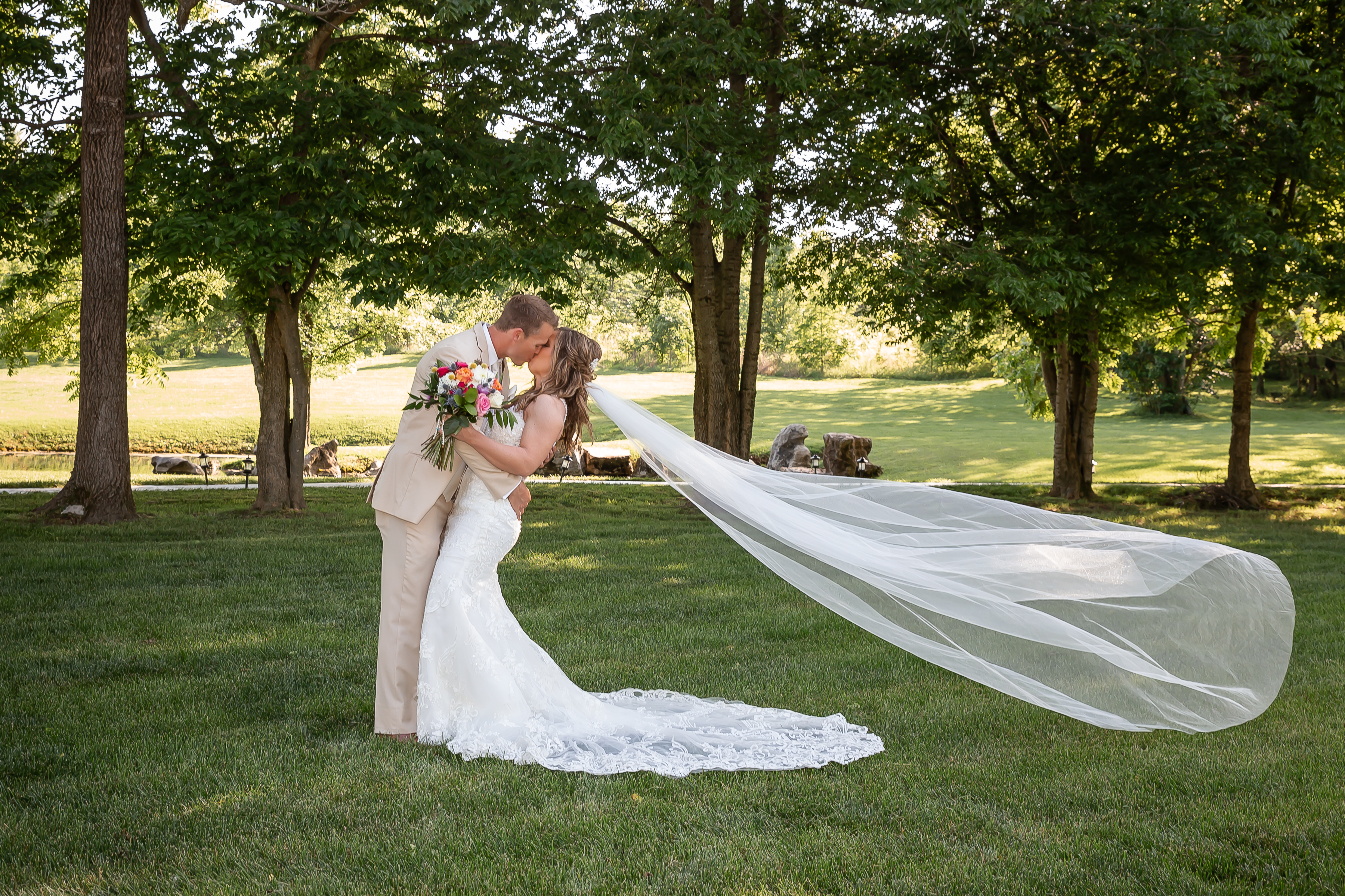 Couple kissing with long veil blowing in the wind at Rusted Route Farms in Jackson, MO