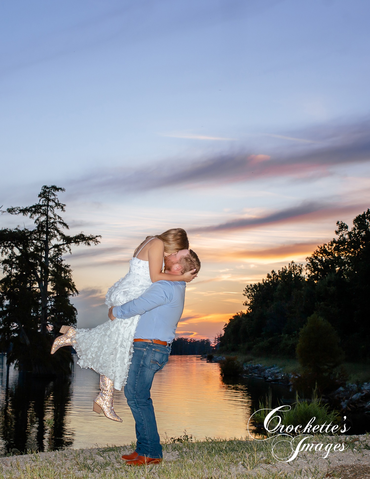 Romantic engagement photo of a couple kissing at sunset at a lake