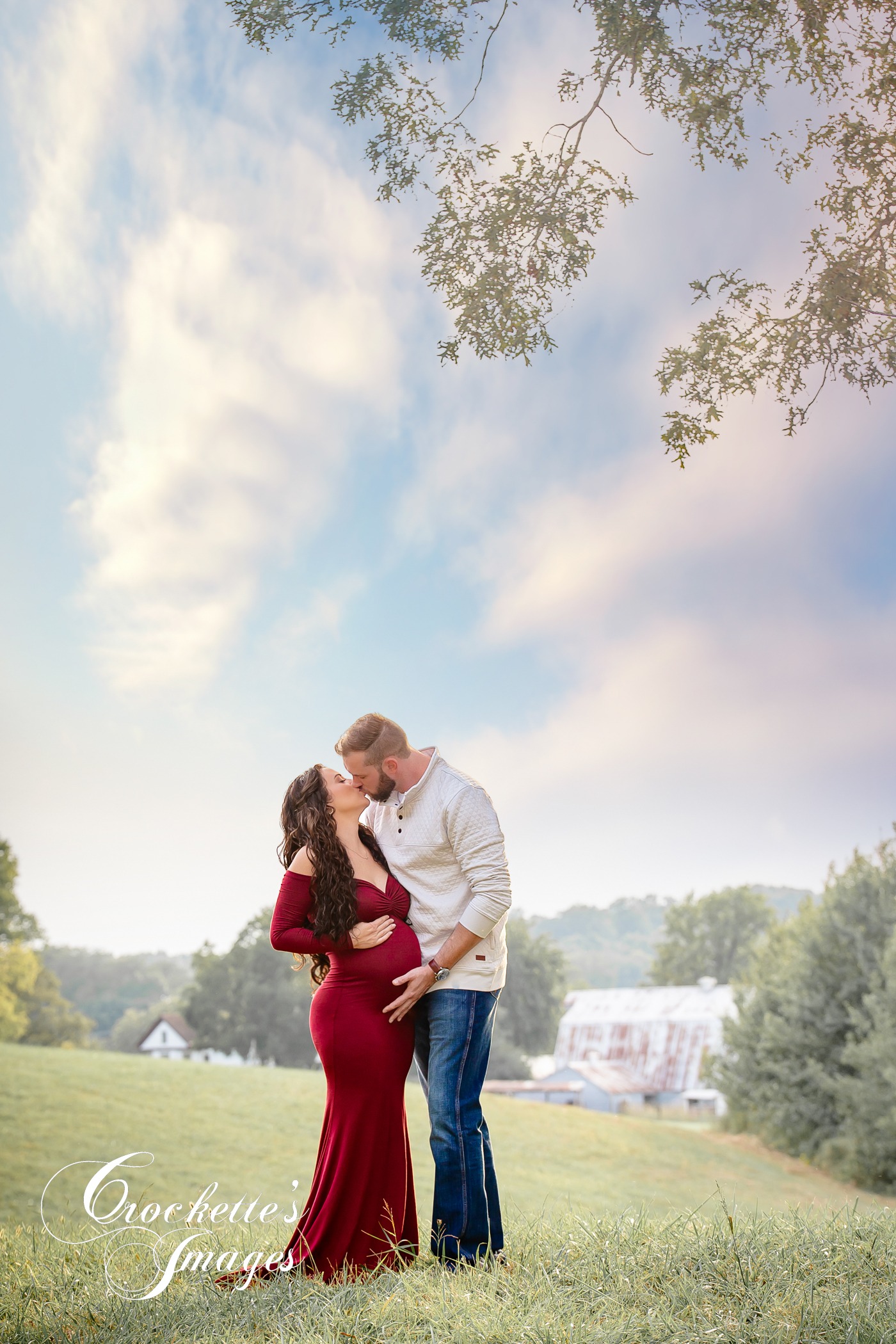 Dreamy engagement photo with couple kissing on a ridge top over looking the farm