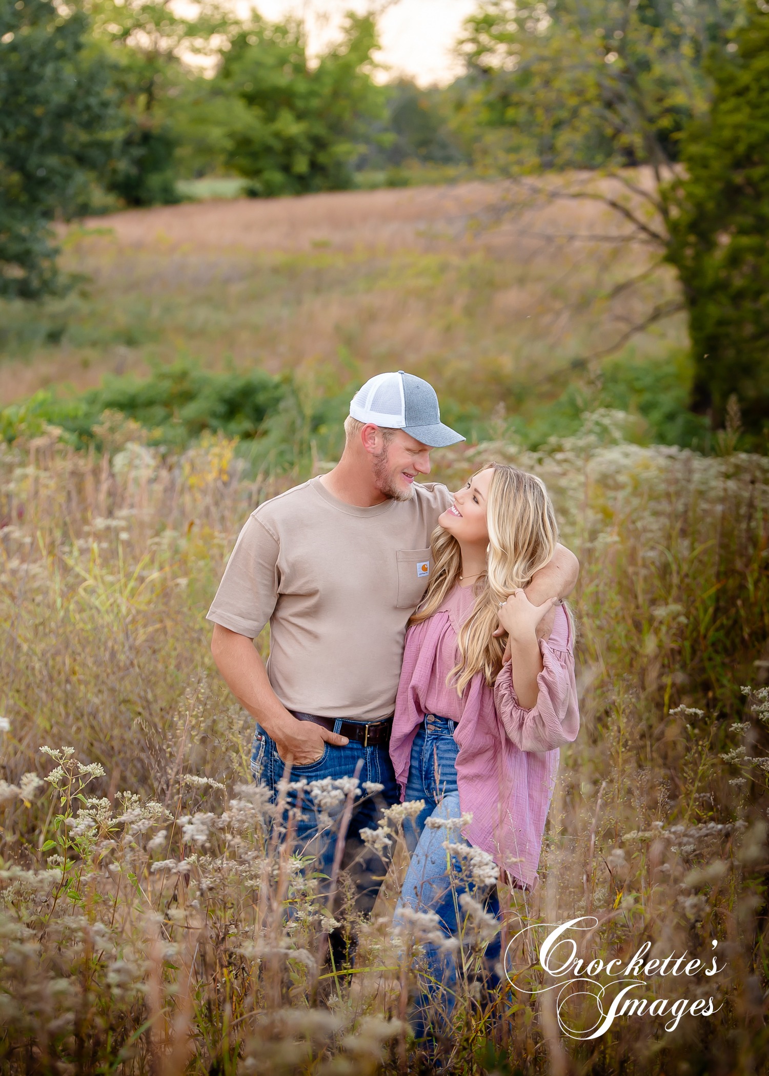 Farm engagement photo with couple standing in a field looking at each other