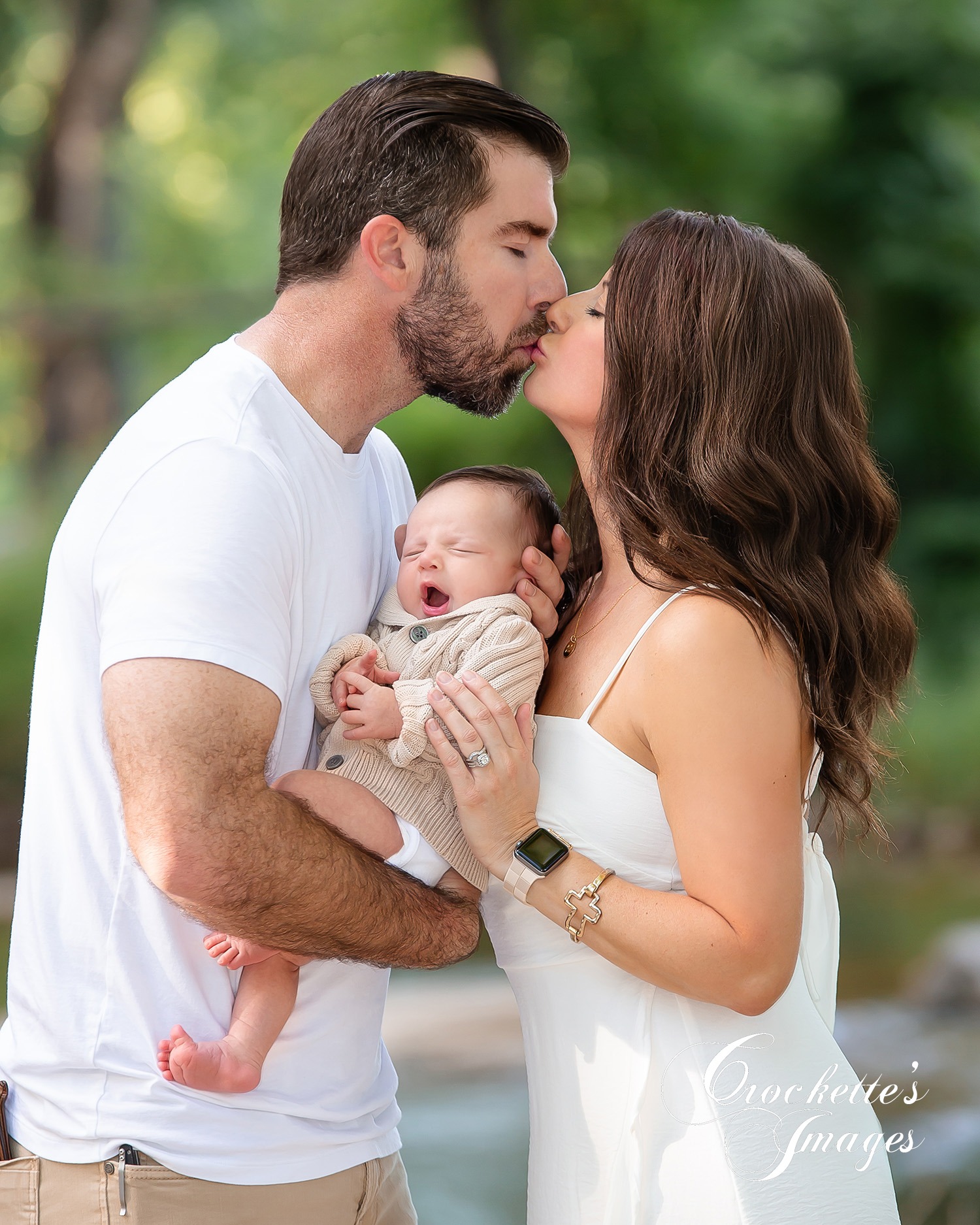 Classy Loving family photo with mom and dad kissing holding a yawning baby