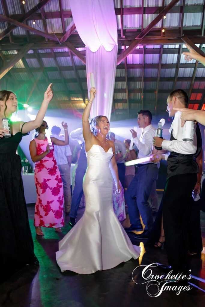 Bride enjoying her wedding day celebration during her reception with dance floor lighting and smoke. 