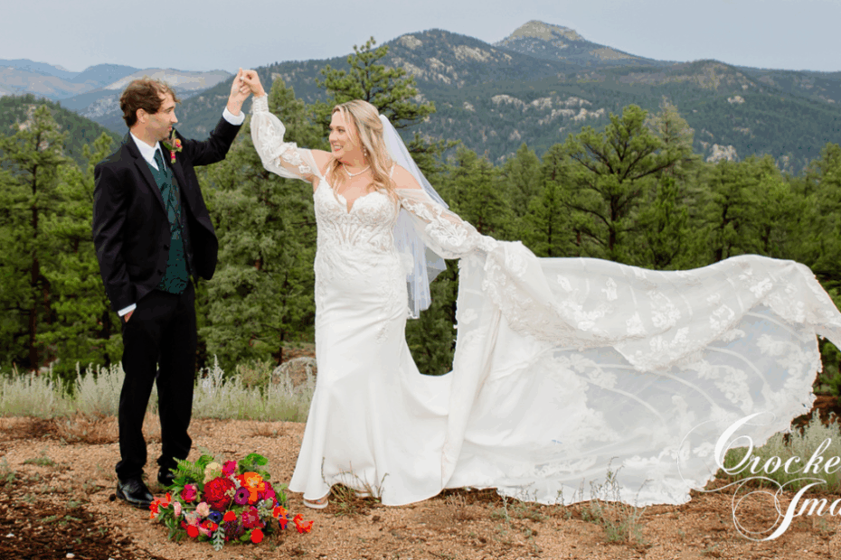Groom spins his new bride with her dress flowing and the mountains in the backdrop.