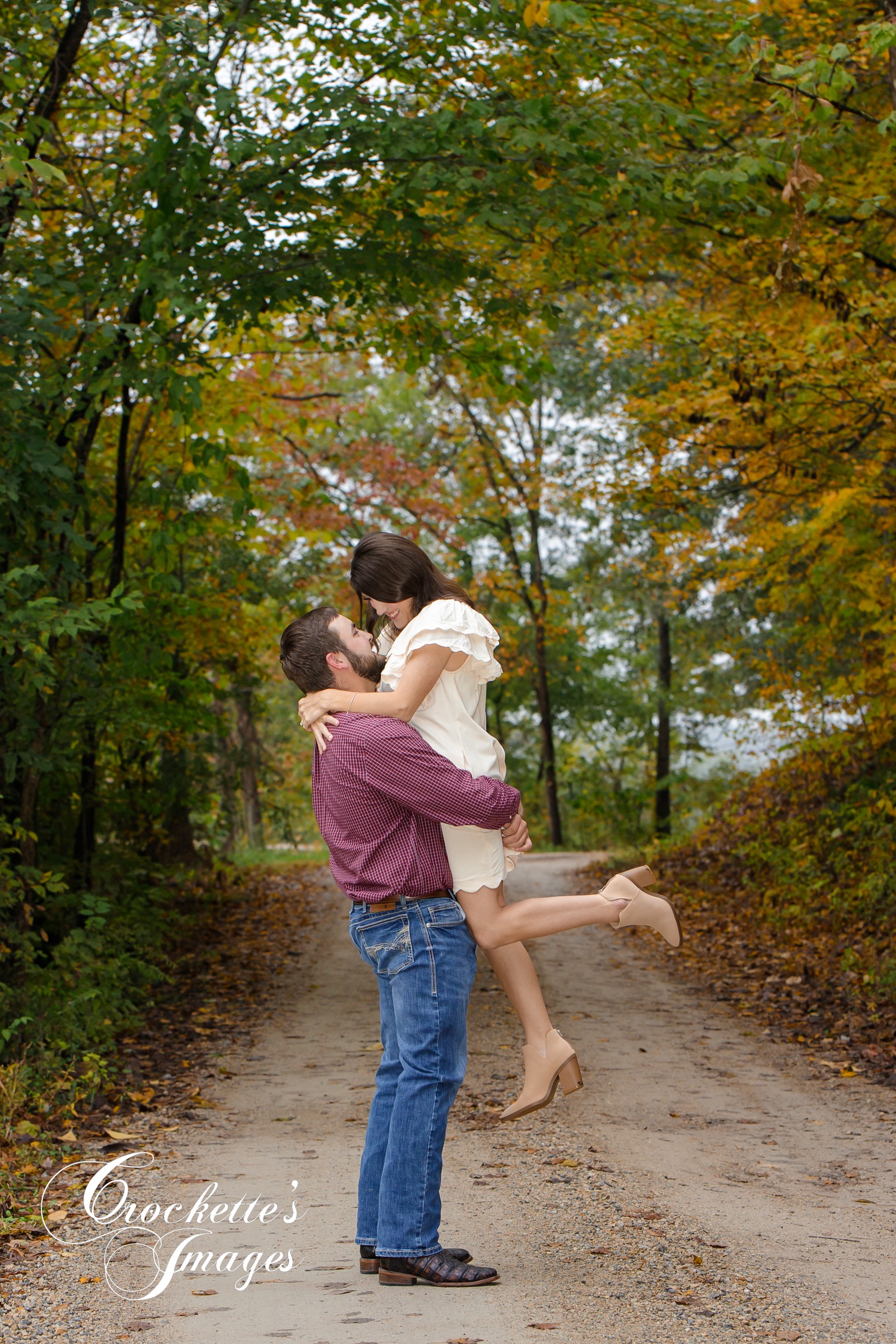 Fall engagement photo on gravel road surrounded with fall leaves