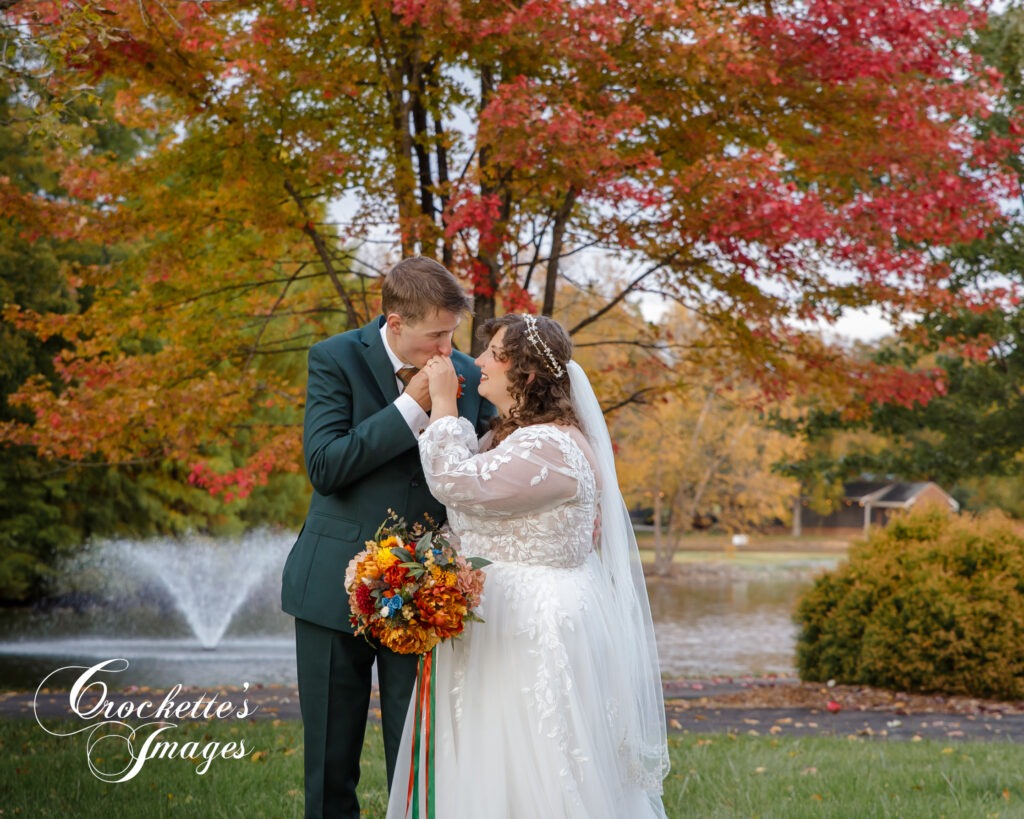 Bride & Groom kissing by the pond at their fall wedding with Crockette's Images at Sweet Pecan Farms in  Cape Girardeau, MO. 