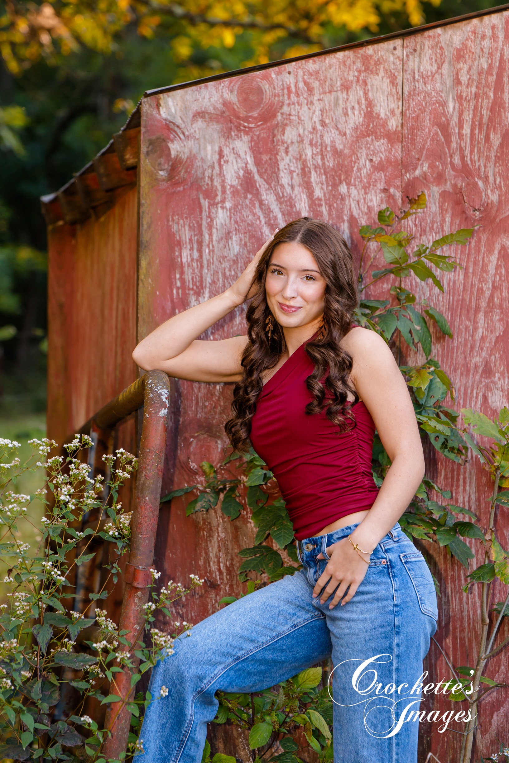 Senior photo of a HIgh School Senior Girl leaning on a rusty gate in front of a red shed