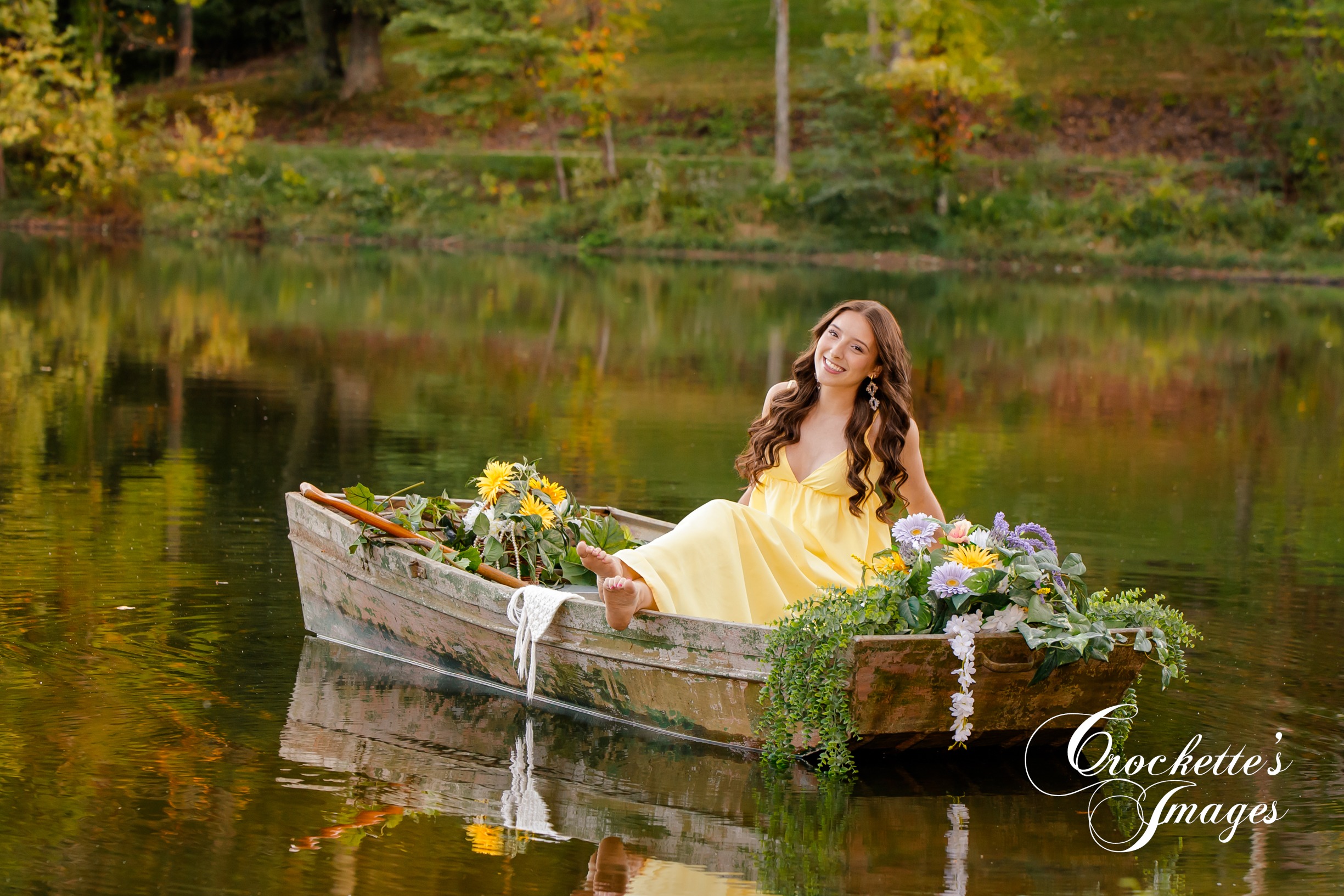 Senior photo of a HIgh School Senior Girl in a boat with flowers on a pond