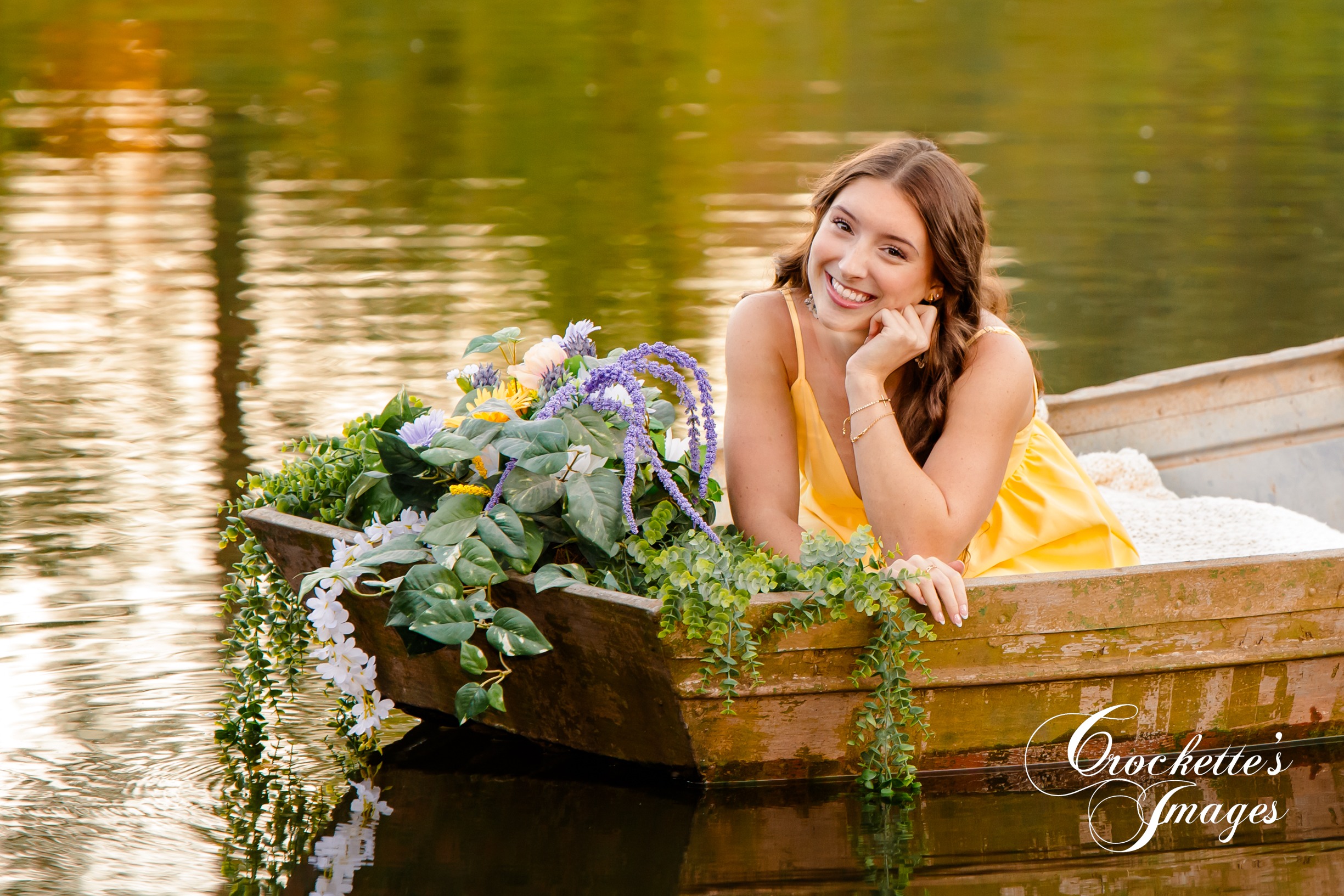 Senior photo of a HIgh School Senior Girl in a boat with flowers on a pond