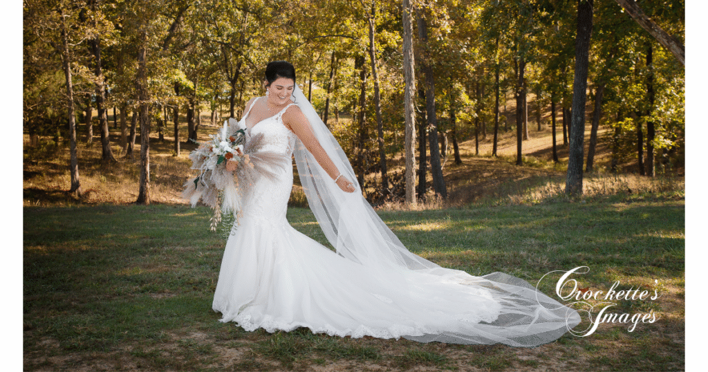 How to Pose With Your Bridal Bouquet for Timeless Wedding Photos You’ll Love Forever 15 Bride poses with her veil and bridal bouquet in front of fall trees.