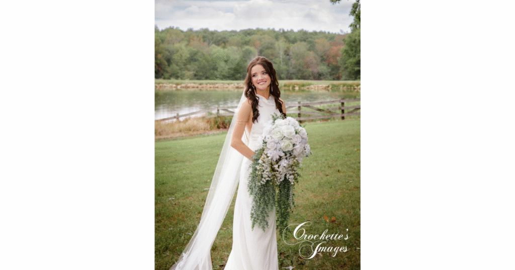 How to Pose With Your Bridal Bouquet for Timeless Wedding Photos You’ll Love Forever 9 Bride poses with her purple, oversized bouquet in a field in front of a pond during a late summer wedding.