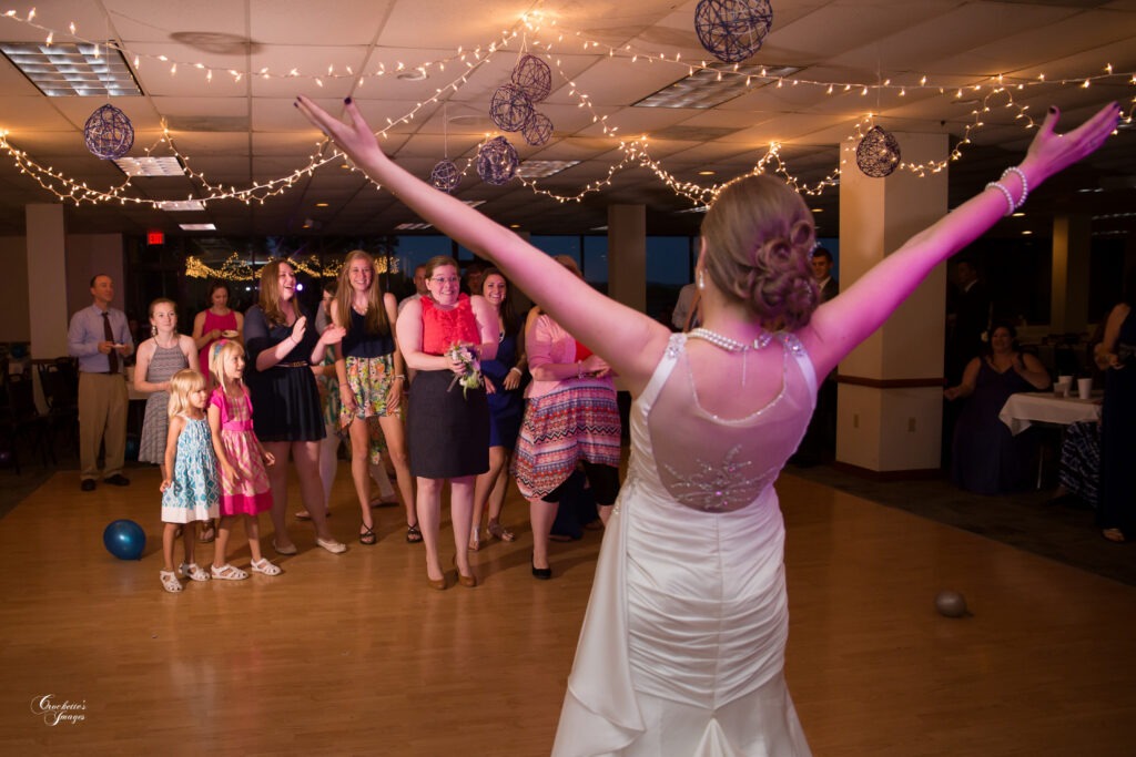 Excited bride celebrating after tossing her bouquet, turning to look at her friends to see who caught it.