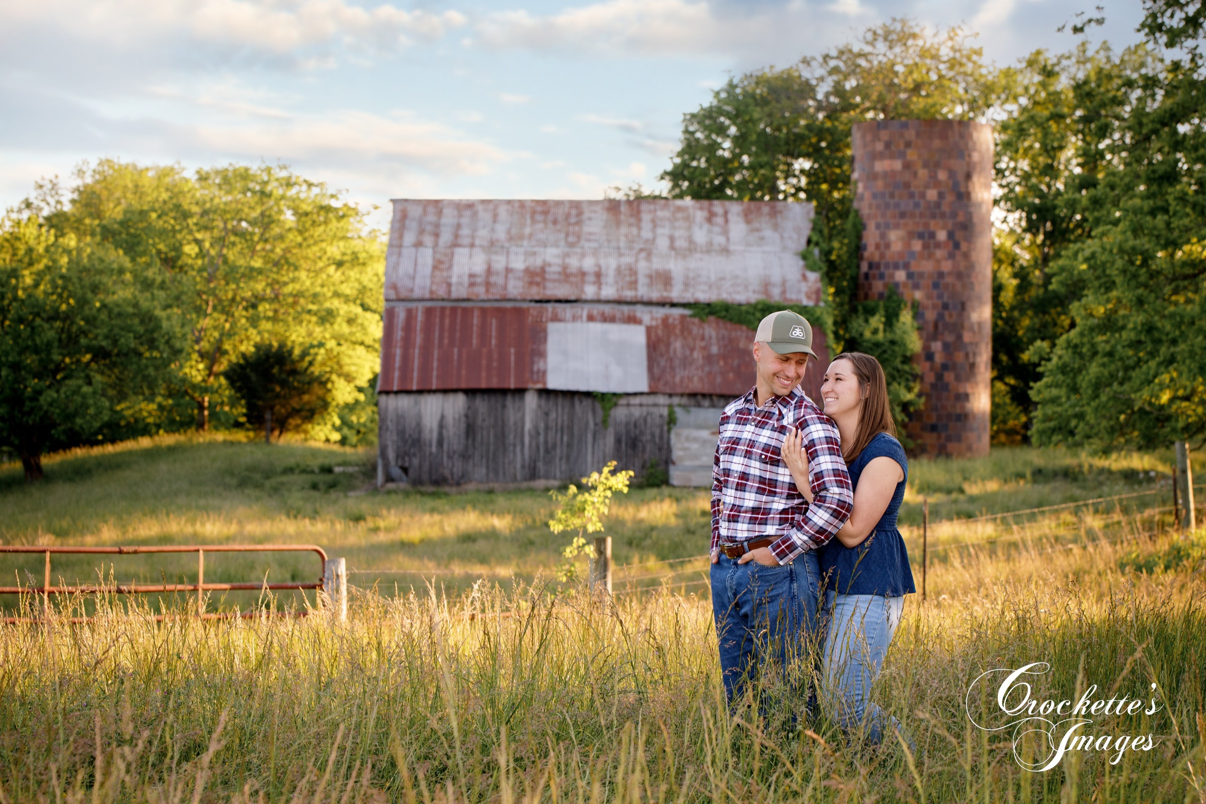 Country engagement photo with Crockette's Images in front of an old barn and silo at sunset