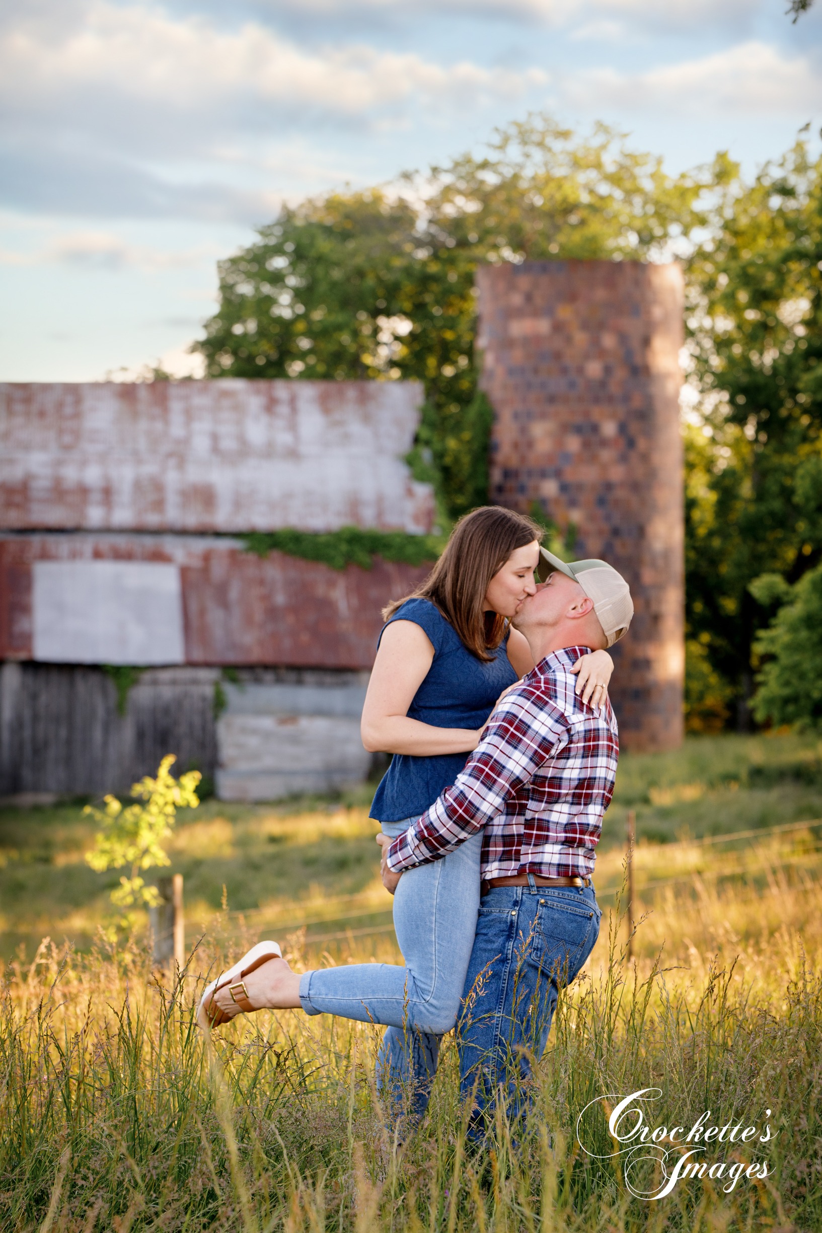 Country engagement photo with Crockette's Images in front of an old barn and silo at sunset