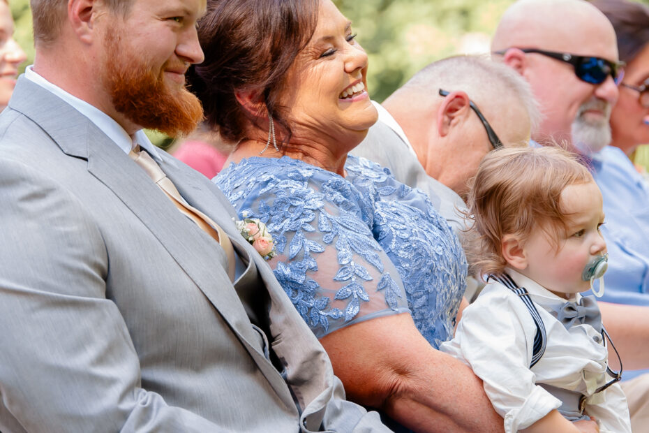 Smiling wedding guests at an outdoor wedding ceremony.